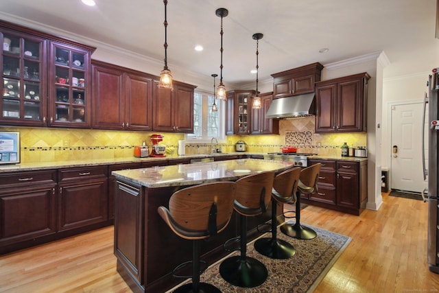 96 Damascus Rd, Branford, CT 06405 - kitchen with a center island, under cabinet range hood, light wood finished floors, decorative light fixtures, and ornamental molding