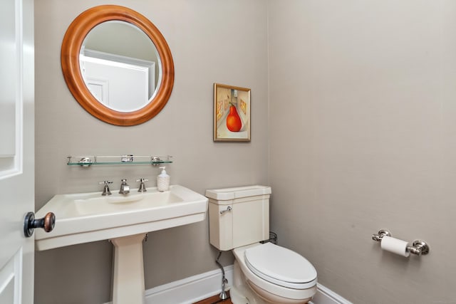 half bathroom with baseboards and toilet