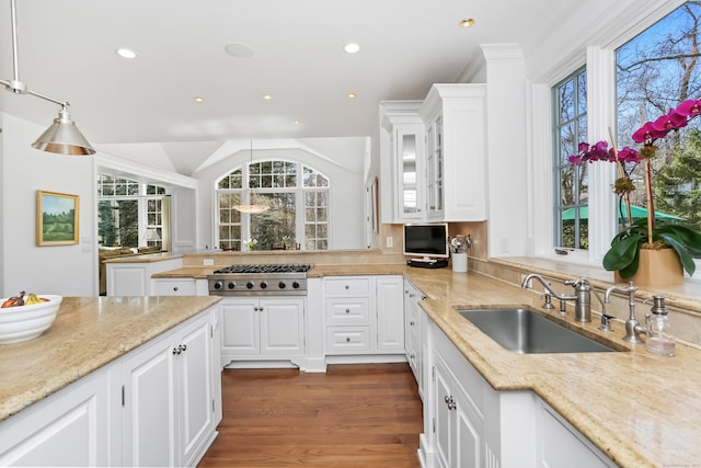 kitchen featuring light stone countertops, a sink, stainless steel gas stovetop, glass insert cabinets, and white cabinets