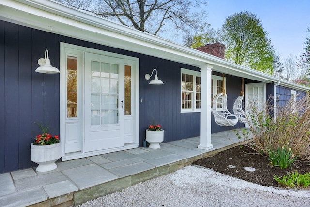 property entrance featuring covered porch and a chimney