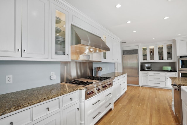 kitchen featuring white cabinetry, stainless steel appliances, light wood-type flooring, and ventilation hood