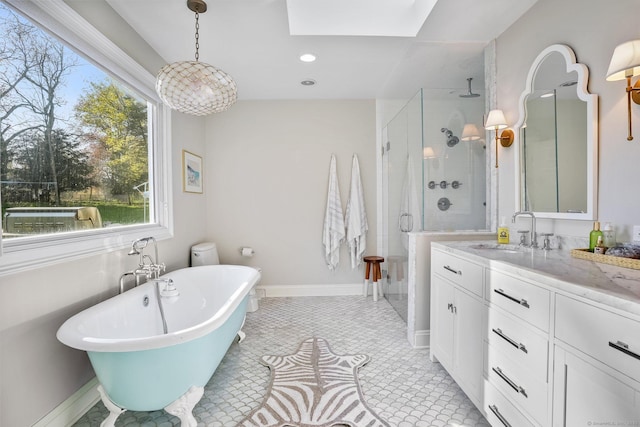 full bath with a stall shower, baseboards, a freestanding tub, vanity, and a skylight