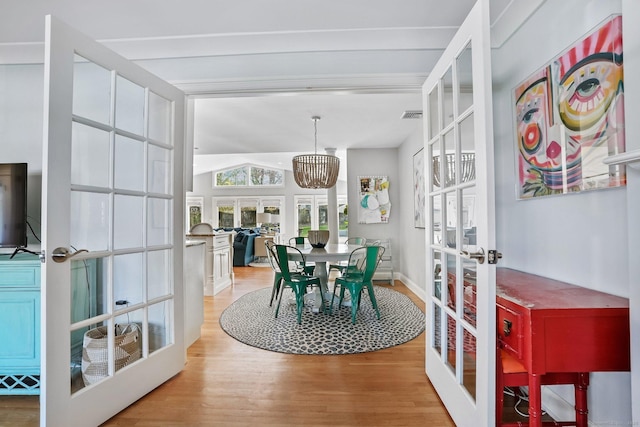 dining area with visible vents, light wood-style flooring, baseboards, french doors, and lofted ceiling