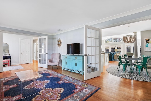 living room featuring french doors, crown molding, baseboards, and light wood-style floors