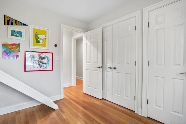 unfurnished bedroom featuring baseboards, light wood-style floors, and a closet