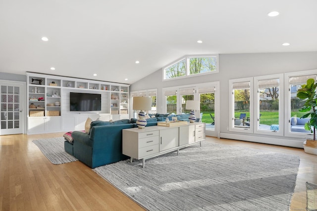 living area with a baseboard heating unit, light wood finished floors, built in features, and vaulted ceiling