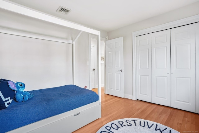 bedroom featuring visible vents, light wood finished floors, and a closet