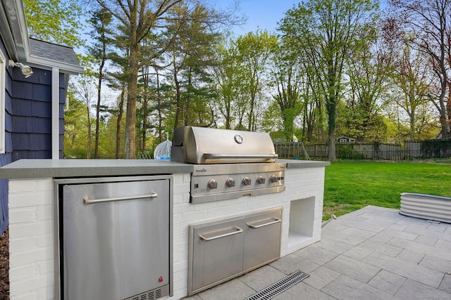 view of patio with area for grilling, grilling area, and fence