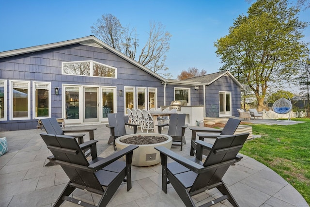 rear view of property with a lawn, a patio area, exterior bar, and an outdoor fire pit