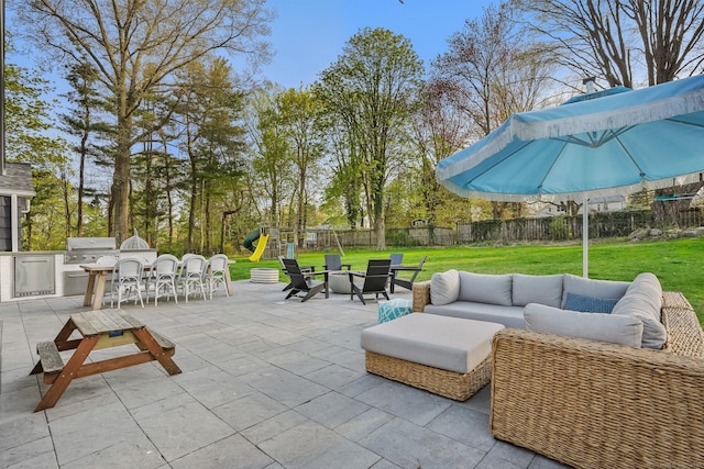 view of patio / terrace featuring an outdoor living space, a fenced backyard, area for grilling, a playground, and exterior kitchen