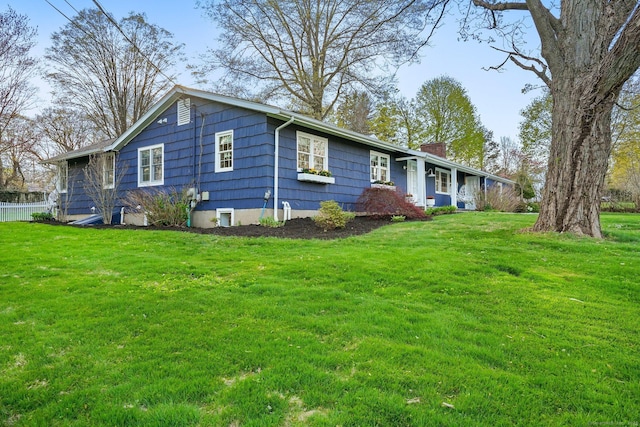 ranch-style home with a chimney, fence, and a front lawn
