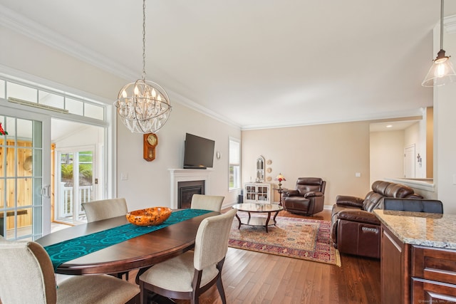 dining space with dark wood finished floors, a fireplace, crown molding, and plenty of natural light