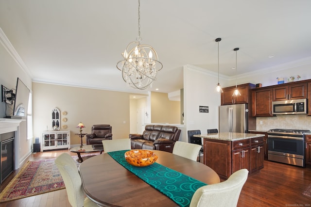 dining room featuring recessed lighting, crown molding, dark wood-style floors, a notable chandelier, and a glass covered fireplace