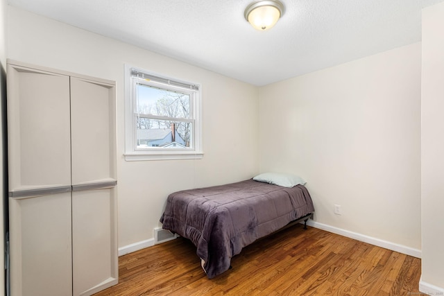 bedroom featuring baseboards, light wood-style flooring, and visible vents