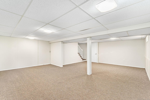 finished basement featuring stairway, carpet floors, baseboards, and a drop ceiling