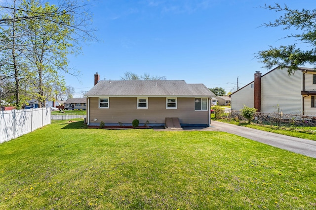 rear view of property featuring fence and a lawn