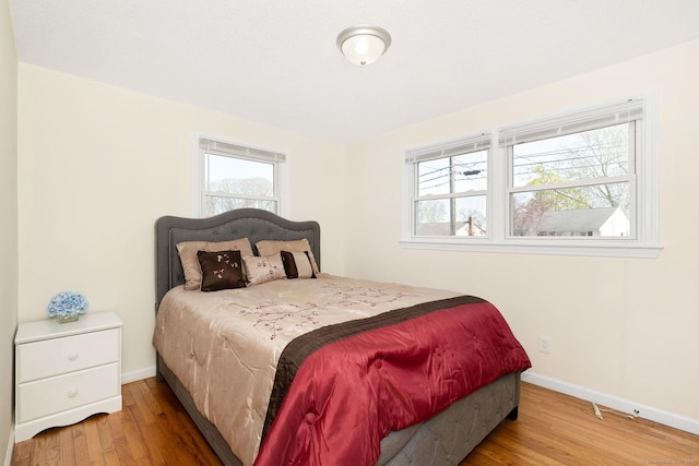 bedroom featuring baseboards, multiple windows, and wood finished floors