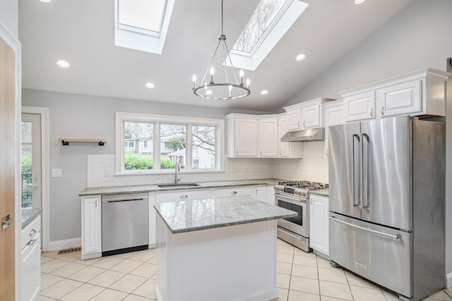 kitchen featuring lofted ceiling with skylight, under cabinet range hood, a sink, appliances with stainless steel finishes, and backsplash