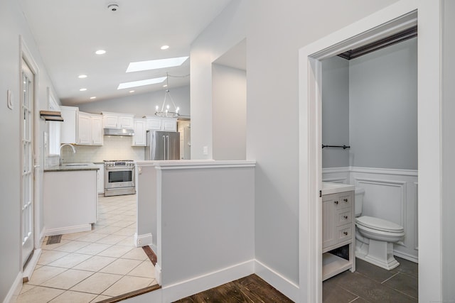 hallway featuring recessed lighting, a sink, lofted ceiling with skylight, and light tile patterned flooring