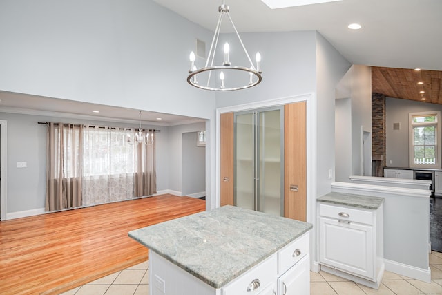 kitchen with white cabinets, a notable chandelier, high vaulted ceiling, a center island, and light tile patterned floors