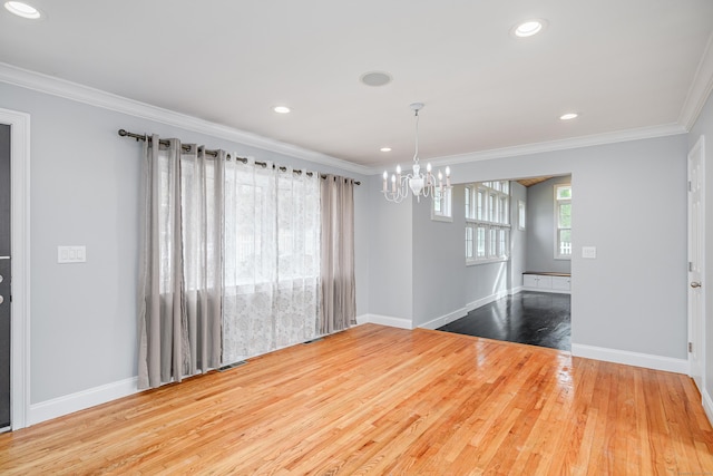 unfurnished dining area featuring crown molding, baseboards, wood finished floors, and a notable chandelier