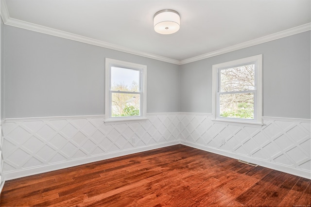 spare room with a wainscoted wall, ornamental molding, and dark wood finished floors