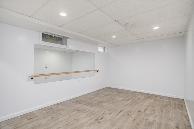 finished below grade area featuring baseboards, recessed lighting, a drop ceiling, and wood finished floors