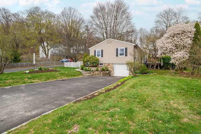 view of property exterior with fence, stone siding, a garage, a yard, and driveway