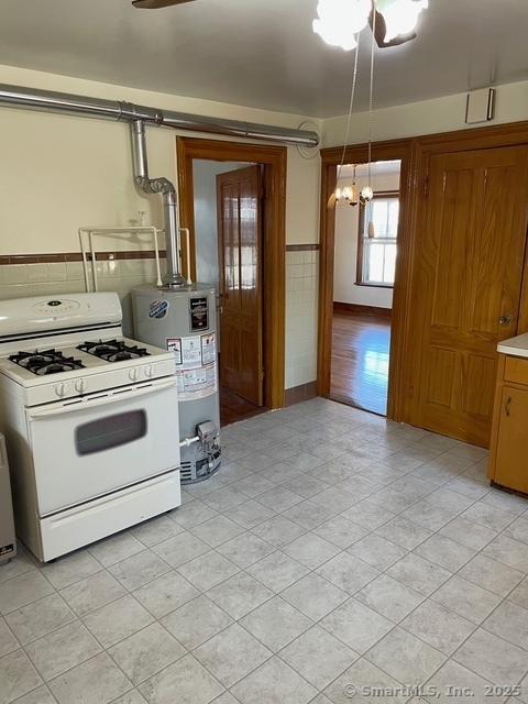 302 High St, Naugatuck, CT 06770 - kitchen featuring white range with gas stovetop, water heater, an inviting chandelier, a wainscoted wall, and light countertops