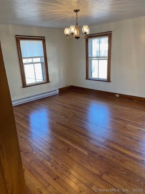 302 High St, Naugatuck, CT 06770 - spare room with baseboard heating, dark wood finished floors, an inviting chandelier, and a wealth of natural light