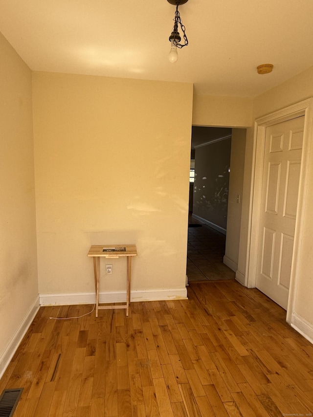 unfurnished dining area with baseboards, wood finished floors, and visible vents