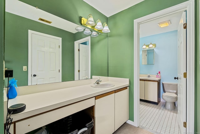 bathroom featuring vanity, toilet, baseboards, and tile patterned flooring