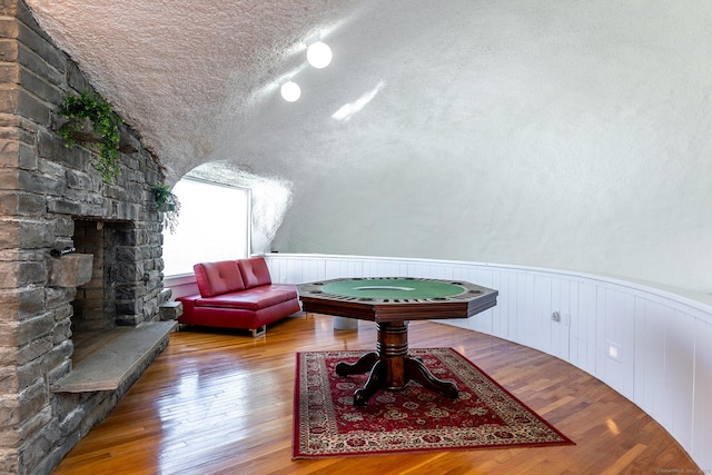 155 Shortwoods Rd, New Fairfield, CT 06812 - sitting room with wood finished floors, lofted ceiling, wainscoting, a textured ceiling, and a stone fireplace