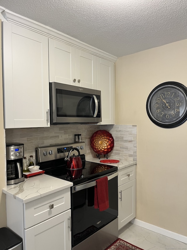 3699 Broadbridge Ave Unit 234, Stratford, CT 06614 - kitchen featuring baseboards, stainless steel appliances, backsplash, white cabinetry, and a textured ceiling