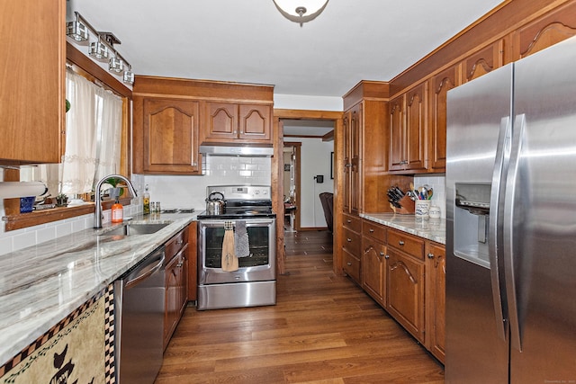 kitchen featuring light stone counters, wood finished floors, a sink, stainless steel appliances, and under cabinet range hood