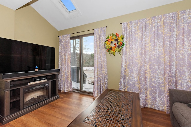 living area with wood finished floors and lofted ceiling with skylight
