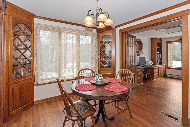 dining space featuring hardwood / wood-style floors, an inviting chandelier, visible vents, crown molding, and a baseboard radiator