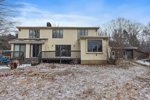 snow covered property featuring a wooden deck and a chimney