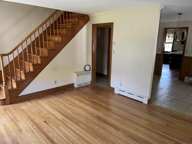 unfurnished living room featuring radiator heating unit, crown molding, stairs, wood finished floors, and a baseboard heating unit