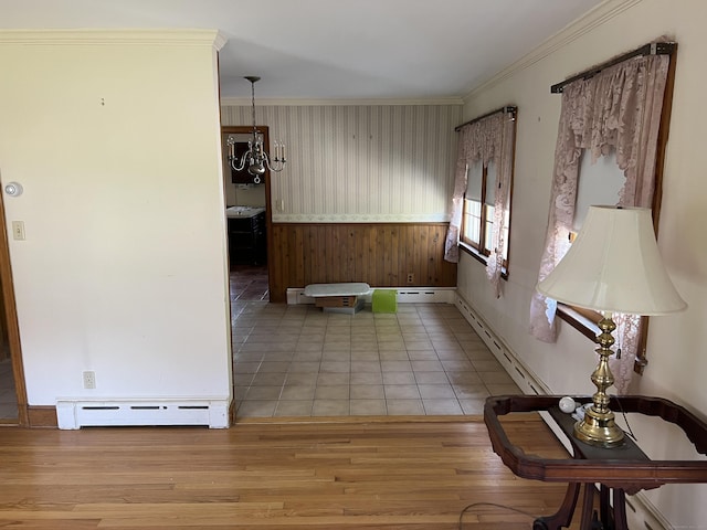 interior space with a wainscoted wall, wooden walls, wood finished floors, baseboards, and a baseboard radiator