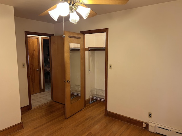 unfurnished bedroom with light wood finished floors, baseboards, a closet, ceiling fan, and a baseboard radiator