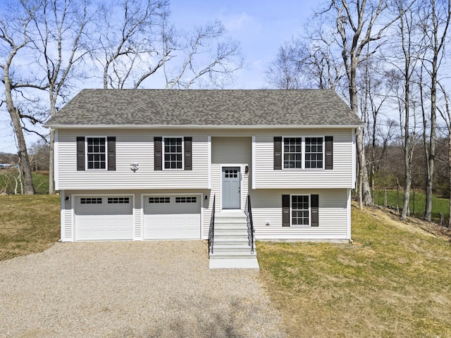 bi-level home featuring a shingled roof, driveway, a front yard, and a garage