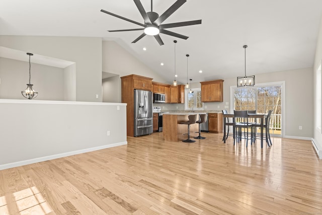 kitchen featuring light wood-type flooring, appliances with stainless steel finishes, brown cabinets, light countertops, and a breakfast bar area