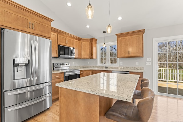 kitchen with stainless steel appliances, vaulted ceiling, a kitchen island, and brown cabinetry