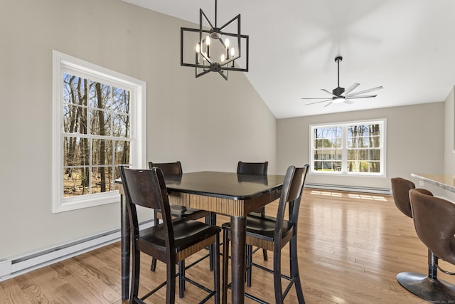 dining space featuring vaulted ceiling, a baseboard heating unit, light wood-style floors, baseboard heating, and ceiling fan with notable chandelier