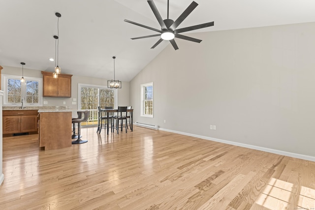 dining room featuring a baseboard heating unit, plenty of natural light, high vaulted ceiling, and light wood-style flooring