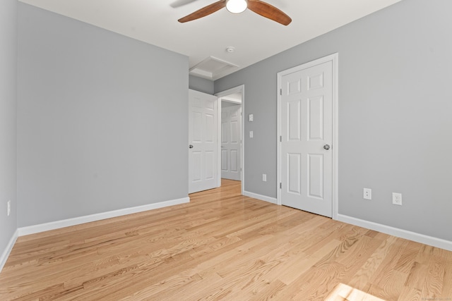 unfurnished bedroom featuring attic access, baseboards, and wood finished floors