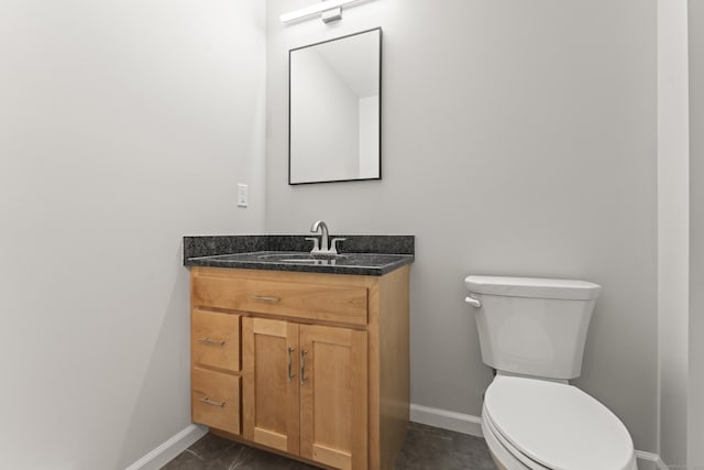 half bath with vanity, toilet, and baseboards
