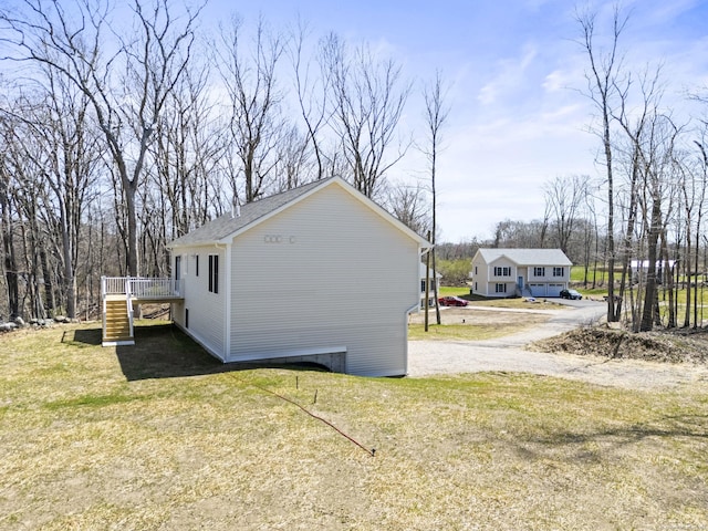 view of property exterior with a wooden deck, a lawn, and stairs