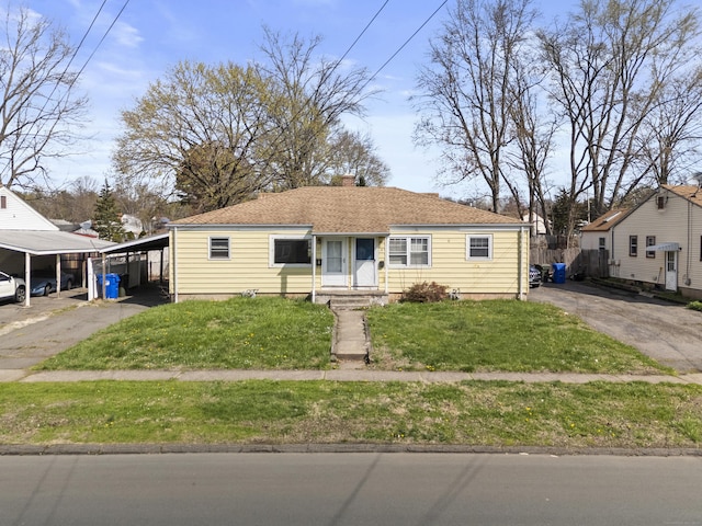 view of front of house featuring driveway, a chimney, a front yard, and an attached carport